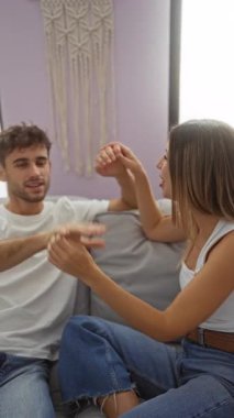 Sıcak oturma odasındaki kanepede uzanan ve duvarında makrome sanat olan çift, samimi bir ev ortamında ahenk ve bağlantıyı tasvir ediyor, sevgi ve rahatlığı vurguluyor..