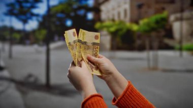 Kentsel bir sokak ortamında elinde Macar forint banknotları tutan kadın, döviz ve ekonomi odaklı iş ve finans temaları vurgulanıyor.