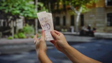 Kentsel bir sokakta tek başına banknotlar sayan bir adam, açık hava ortamındaki yatırımları ve finansal faaliyetleri vurguluyor..