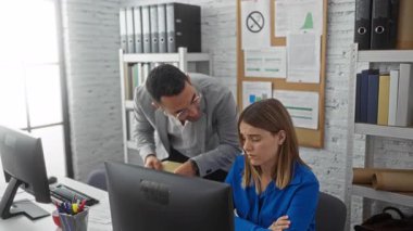 Kadın ve erkek, modern bir ofiste bilgisayarlarla ve kitaplıklarla ciddi bir iş yeri sohbeti olduğunu belirten belgeleri yoğun bir şekilde tartışırlar..