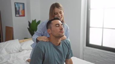 Çift, sıcak bir yatak odasında, bir kadının erkeğe nazik bir masaj yaparak, evde huzurlu ve samimi bir atmosfer yaratmasıyla, sevgi dolu bir anı yaşıyor..