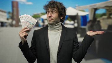 Suudi riyallerini şehir sokaklarında sergileyen İspanyol bir adam, hareketli bir şehir manzarasında finansal başarıyı ön plana çıkarıyor..