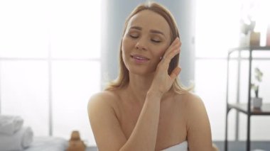 Huzurlu güzellik salonunda rahat bir spa deneyimi yaşayan bir kadın sıcak bir ortam yaratarak kendine bakmada ve sağlıkta mutluluk ve rahatlık sergiliyor..