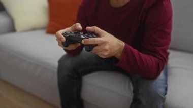 Modern apartman dairesinde video oyunları oynayan genç bir adam rahat gri bir kanepede otururken....