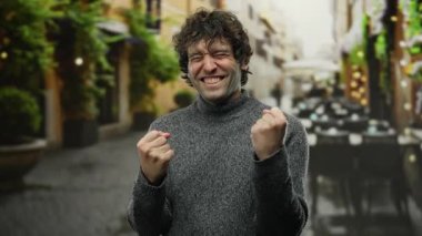 Şehir sokaklarında neşeli bir ifadeyle kutlayan bir adam, bir şehir zeminine karşı mutluluk ve başarı çağrıştırıyor, canlı ve canlı bir atmosfer yaratıyor..
