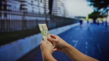 Kalabalık bir şehir ortamında iş ve yatırım fırsatları gösteren bir şehir caddesinde Hong Kong doları sayan bir adam..