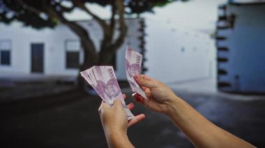 Finansal işlemler ve karşılıklı çıkarımlara odaklanmış bir şehir ortamında Endonezya parası sayan eller.