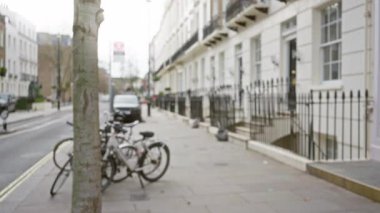 Soğuk bir mevsimde Londra 'da bisikletli, kaldırımlı ve binalı bulanık sokak sahnesi, İngiltere' de şehir yaşamını gözler önüne seriyor..