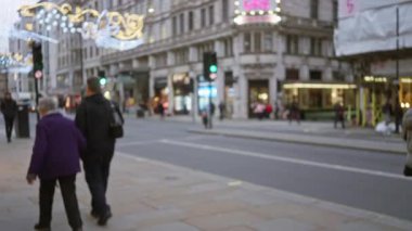 İnsanlar kış boyunca kalabalık bir Londra caddesinde şenlikli dekorasyonlar, bulanık ışıklar ve Birleşik Krallık 'taki hareketli şehir atmosferiyle yürüyorlar..