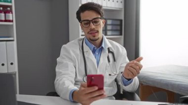 Steteskoplu bir doktor iletişim için kliniğin içindeki akıllı telefonu kullanıyor..