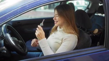 Kadın elinde anahtar, şehir ortamında gülerek gündüz vakti açık havada rahat ve kendinden emin bir tavır sergiliyor..