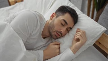 Genç bir adam beyaz çarşaflı bir yatak odasında huzur içinde uyuyor. İçerideki huzur ve rahatlığı somutlaştırıyor..