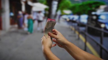 Kalabalık bir şehir caddesinde Endonezya rupiasını tutan adam, arka planda insanlarla kentsel ticareti gözler önüne seriyor, bir şehirde para değişimi vurguluyor..