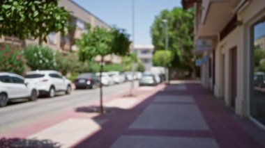 Açık hava manzarası bulanık. Güneşli havada kaldırım boyunca ağaçlar ve arabaların odağını kaybetmiş.