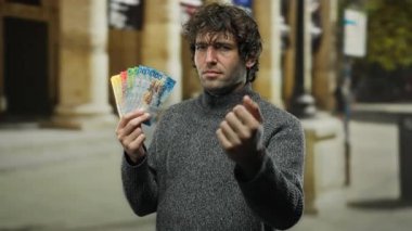 İsviçre frangı banknotlarını elinde tutan adam bir şehir caddesinde güven içinde açık havada servetini temsil ediyor.