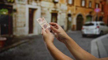 Bir şehir caddesinde Meksika pezosu tutan eller, para birimi ve mali bağlamda iş, yatırım ve şehir yaşamını ön plana çıkarıyor.