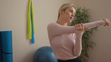 Bir kadın spor salonunda ekipmanlarıyla esniyor, spor ve sağlığa odaklanıyor. Parlak bir odada spor yapmaya ve sağlıklı bir yaşam tarzına kendini adamış.