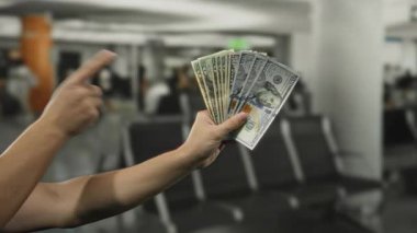Kapalı hava alanında elinde Amerikan doları olan başarılı bir seyahat ya da finansal kazancı ön plana çıkaran bir adam..