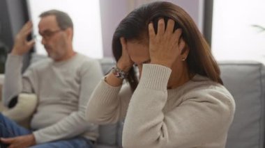 Orta yaşlı İspanyol bir çift evde oturmuş stresli ve üzgün görünüyor. Erkekler düşünceli görünürken kadınlar başlarını tutuyor..