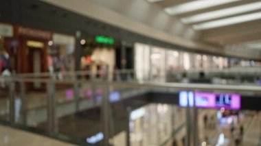 Bulanık mağaza vitrinleriyle modern bir alışveriş merkezinin odaklanmamış görüntüsü, canlı bokeh görüntüsü ve geniş, modaya uygun bir perakende ortamında odak dışı müşteriler.