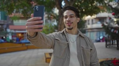 Kentsel parktaki İspanyol adam Sunny Caddesi 'ndeki akıllı telefonuyla görüntülü görüşme yapıyor.