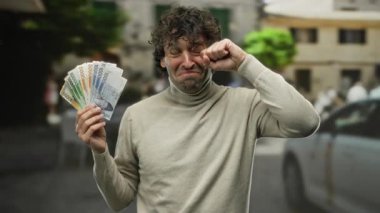 Güney Kore banknotlarını elinde tutan ve ağlayan İspanyol bir adam şehir ortamında duygularının bir karışımını sergiliyor..