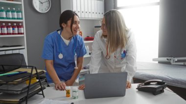 Tıbbi malzemeler ve dizüstü bilgisayarla klinikteki İspanyol kadın doktorlar sağlık ortamında takım çalışması sunuyorlar..