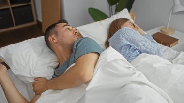 Bir erkek, rahat bir yatak odasında yanında uyuyan kadına bakar. Evinde huzurlu bir aşk ve yakınlık sahnesi sergiler..