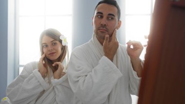Spa elbiseli ve cilt bakımından hoşlanan sakin bir sağlık merkezinde sakin ifadeler takınan bir çift, rahatlama ve samimiyeti yansıtıyor..