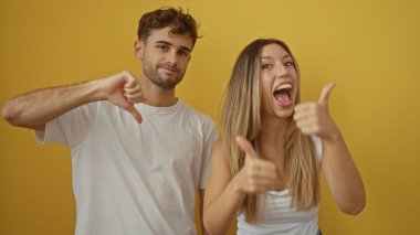Kadın ve erkek, izole edilmiş stüdyo ortamında canlı sarı arkaplan karşısında ters tepkiler veriyorlar..