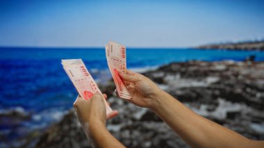 Tayvan banknotlarını deniz kenarında tutan adam, arka planda okyanus olan bir açık alanda yatırım ve finansal kavramları vurguluyor..