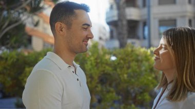Şehir parkında birbirine gülümseyen bir adam ve kadın güzel bir şehir ortamında aşk ve bağlantı anlarını yakalıyorlar..