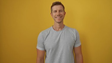 Genç adam canlı sarı bir arkaplan karşısında güvenle gülümsüyor. Modern pazarlama ve yaşam tarzı teması için ideal ve sıradan bir portre sergiliyor..