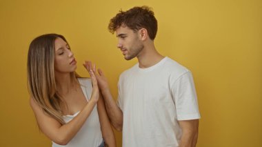 Sarı bir arka plana karşı birlikte duran erkek ve kadın basit ve izole bir ortamda bir bağ ve güzel bir ilişki sergiliyorlar..