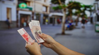 Bir şehir caddesinde İzlanda Krona banknotları tutan bir adam, para değişimi ve kentsel bir ortamda yatırım fırsatları sergiliyor.