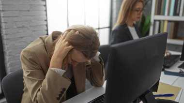 Ofiste çalışan kadınlar, iş yerindeki sarışın profesyonellerin kapalı alanda yaşadığı baskıyı vurgulayan bilgisayar ve belgelerle çalışmanın önemini vurguladılar..