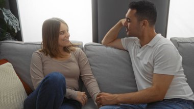 Kadın ve erkek rahat bir oturma odasında kanepede oturuyor, evlerinde neşeli bir anı paylaşıyorlar, sıcaklığı, sevgiyi ve İspanyol kültürünü somutlaştırıyorlar..