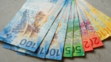 İsviçre banknotları, renkli İsviçre franklarını vurgulamak için beton bir yüzeyde bir vantilatöre yerleştirilmiş çeşitli banknotlar..