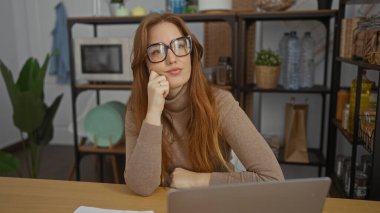 Samimi bir ofiste dizüstü bilgisayarı olan bir kadın, bitkilerle ve raflarla çevrili, düşünceli bir ortam yaratıyor..