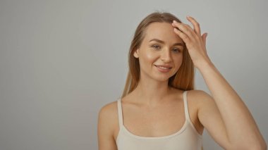 İzole edilmiş beyaz arka planda güvenle gülümseyen bir kadın, sarışın saçlarını ve güzelliğini göstererek, çekici ve doğal bir şekilde ışıldıyor..