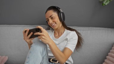 Kapalı bir koltukta oturan, kulaklık takıp gülümseyen, akıllı telefon kullanan, rahat ve teknolojik bir atmosfer yaratan bir kadın..