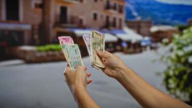 Bir şehir caddesinde Hint rupileri tutan bir adam, açık şehir ortamında banknotları sergiliyor, Hindistan 'daki iş ve finansal işlemleri sembolize ediyor..