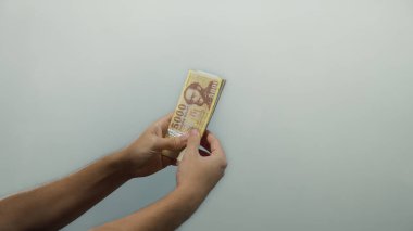 Macar banknotlarını beyaz arka planda tutan adam, izole edilmiş bir ortamda finans ve para birimine odaklanıyor..
