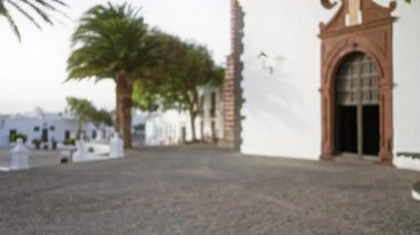 Lanzarote 'daki dış mekan, palmiye ağaçları, beyaz binalar ve tarihi kilise girişi olan kanarya adaları.
