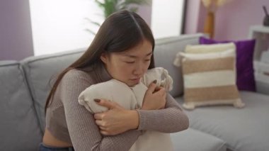 Yastık tutan kadın rahat bir dairede Asyalı güzelliğini ve duygularını evlerinde sergiliyor..