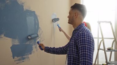 Evin içinde bigudileri olan bir çift, kadın yanında çalışırken gülümseyen bir adam..