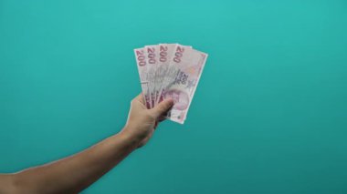 İzole edilmiş yeşil arka plana karşı elinde Türk lirası banknotları tutan adam, ticari amaçlar için finansal konsept ve para birimi temsilciliği sergiliyor