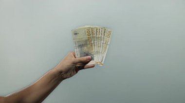 Danimarka kronu banknotlarını beyaz arkaplan üzerinde tutan adam, Danimarka 'dan açık ve izole bir sahnede para sergiliyor, finans ve zenginlik kavramlarını vurguluyor.