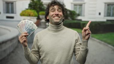 Bir şehir caddesinde elinde Polonya parasıyla gülümseyen İspanyol bir adam, başarıyı ve mutluluğu iletiyor..