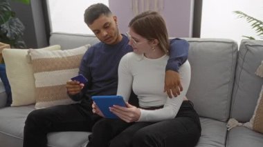 Kadın ve erkek evdeki kanepede dinleniyor, dijital tablet ve kredi kartını paylaşıyorlar, sıcak bir oturma odasında birbirini seven bir çiftin....